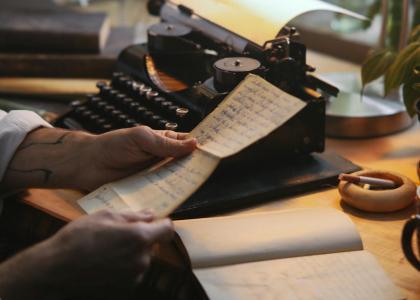 Pessoa lendo carta com máquina de escrever